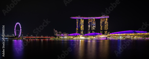 Cityscape in panorama view of night time urban skyscraper with light reflection on the water at Marina bay at Waterfront, Marina bay, Singapore. Tourist spot and attraction.