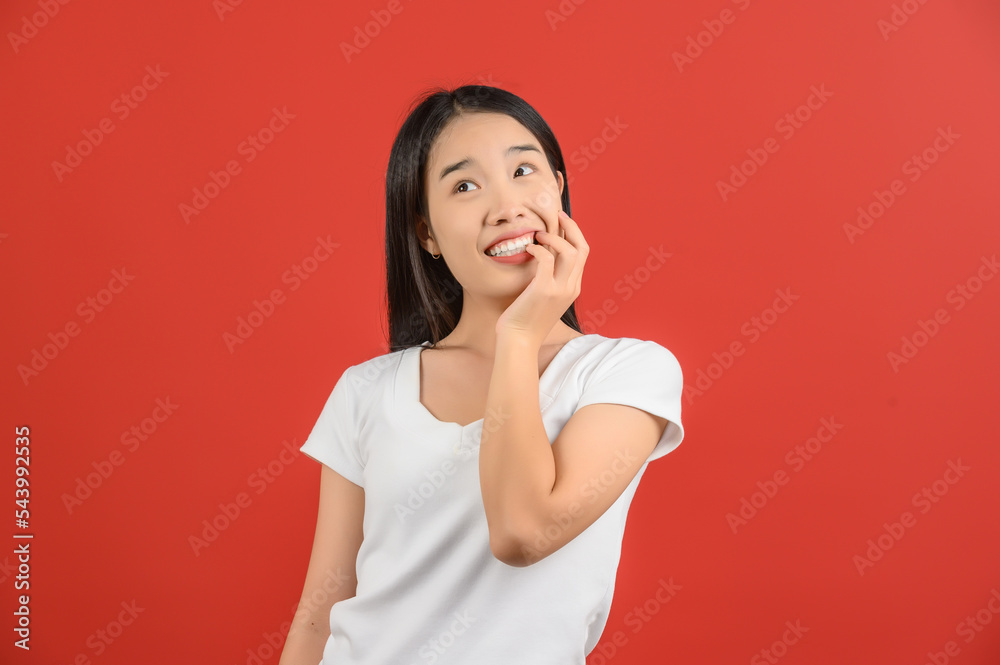 © Johnstocker - Portrait of Happy young asian woman in white t-shirt smiling and looking up isolated on red background