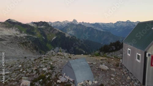 Lone Cabin on Mountain Peak at Sunset with Reveal of Mountain Landscape with Beautiful Golden Hour Horizon on Mount Brew Canada 4K photo