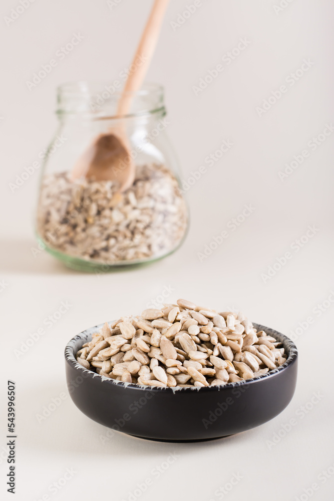 Peeled sunflower seeds in a bowl and in a glass jar on the table. Organic food. Vertical view