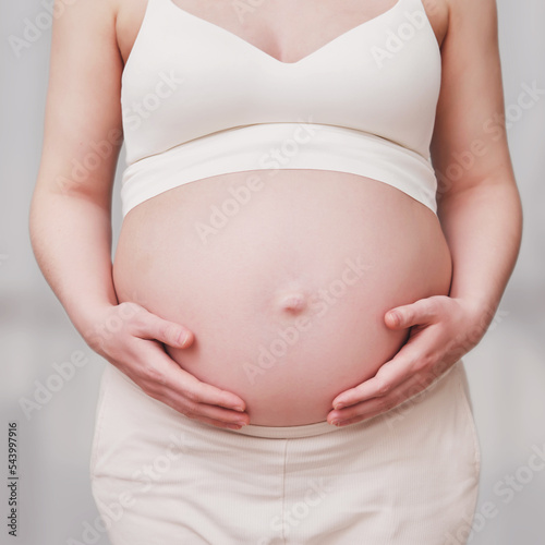 Wallpaper Mural A pregnant woman in white clothes holds her stomach with her hands Torontodigital.ca