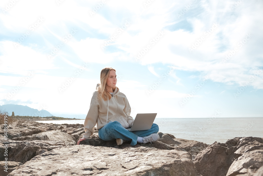 Remote work.Girl freelancer works remotely on the sea shore. workation, remote work,WFVH,Van Life vibes work from vacation home,work travel,remotely work.Travelling.Work from vacation remotely