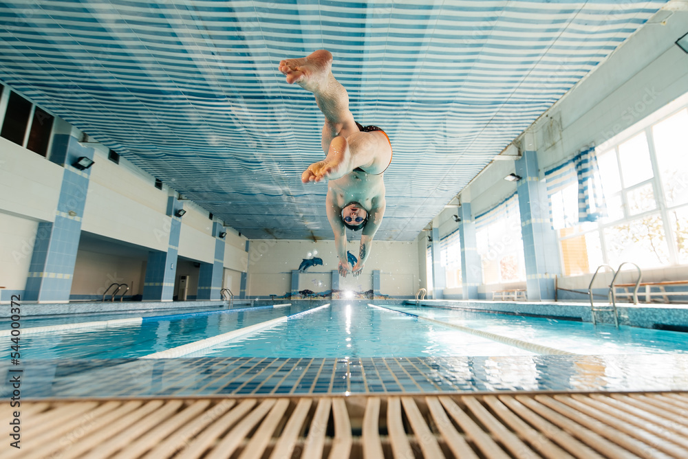 © Andrii - A young man dives and jumps into the water of a modern swimming pool. Training and sports development. Preparation for competitions, and a healthy lifestyle. Water treatments and a healthy lifestyle. © Andrii - A young man dives and jumps into the water of a modern swimming pool. Training and sports development. Preparation for competitions, and a healthy lifestyle. Water treatments and a healthy lifestyle.