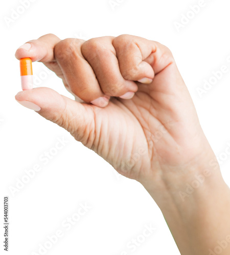 Close up shot of hand holding an orange pill isolated on white