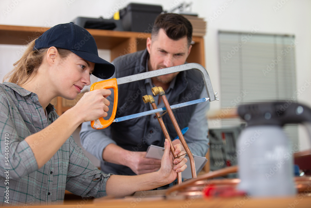 female worker using hacksaw to cut copper pipe Stock Photo Adobe Stock