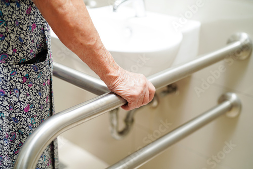 Fotografiet Asian elderly old woman patient use toilet support rail in bathroom, handrail safety grab bar, security in nursing hospital