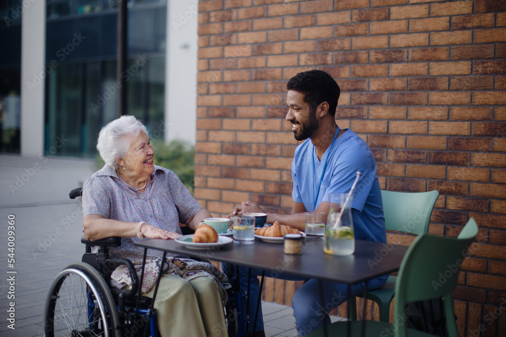 Caregiver having breakfast with his client at cafe. Caregiver having breakfast with his client at cafe.