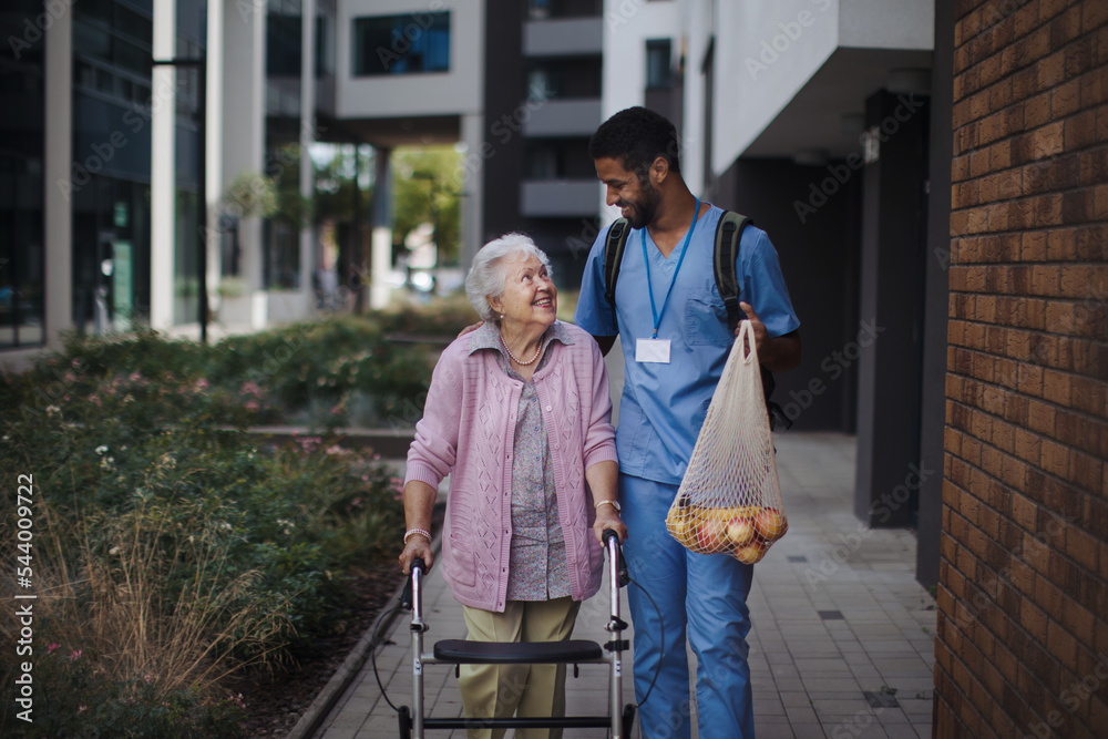 Happy caregiver caming back from grocery with his senior woman client.