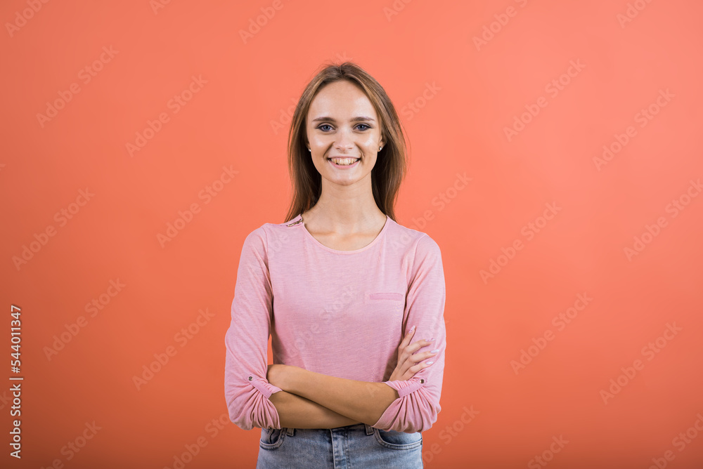 Fototapeta premium Portrait of a happy girl with crossed arms who smiles on a red background.