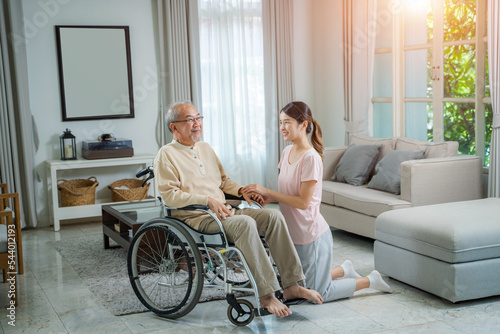 Caregiver woman comforting senior man sitting on wheelchair at nursing home,Loving caregiver taking care and express health care sympathy of senior man. © visoot