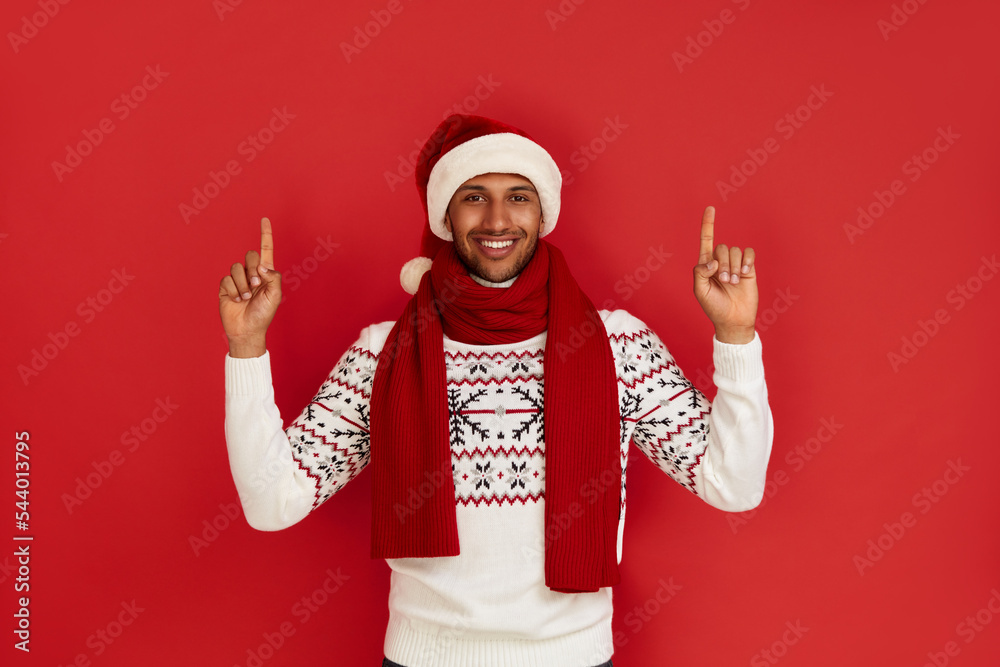 Smiling Man Pointing Hand. Positive Multiracial Guy Pointing Away Paying Your Attention at Empty Space for Advertisement. Indoor Studio Shot Isolated on Red Background Smiling Man Pointing Hand. Positive Multiracial Guy Pointing Away Paying Your Attention at Empty Space for Advertisement. Indoor Studio Shot Isolated on Red Background