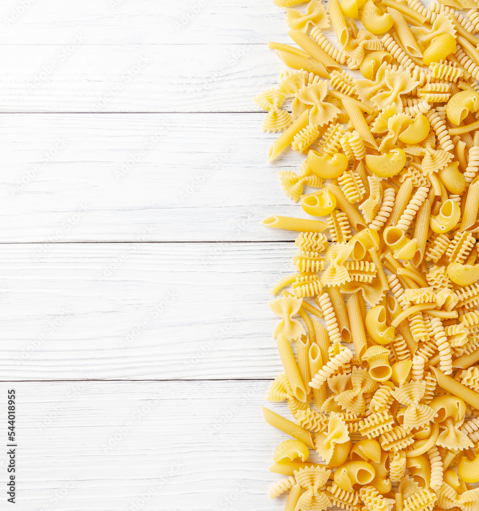 Different types and shapes of Italian pasta on white wooden background