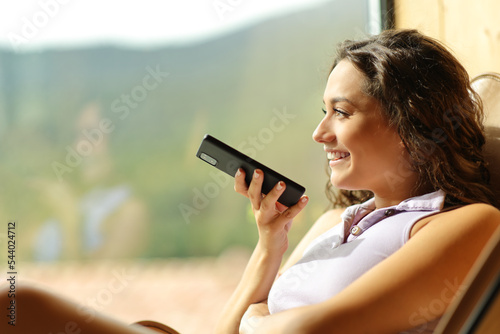 Foto Happy woman on a chair dictating message on phone