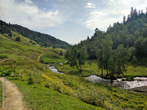 Beautiful view of the landscape of the Caucasus mountains. The river flows along the green hills. Arkhyz, Karachay-Cherkessia, Russia