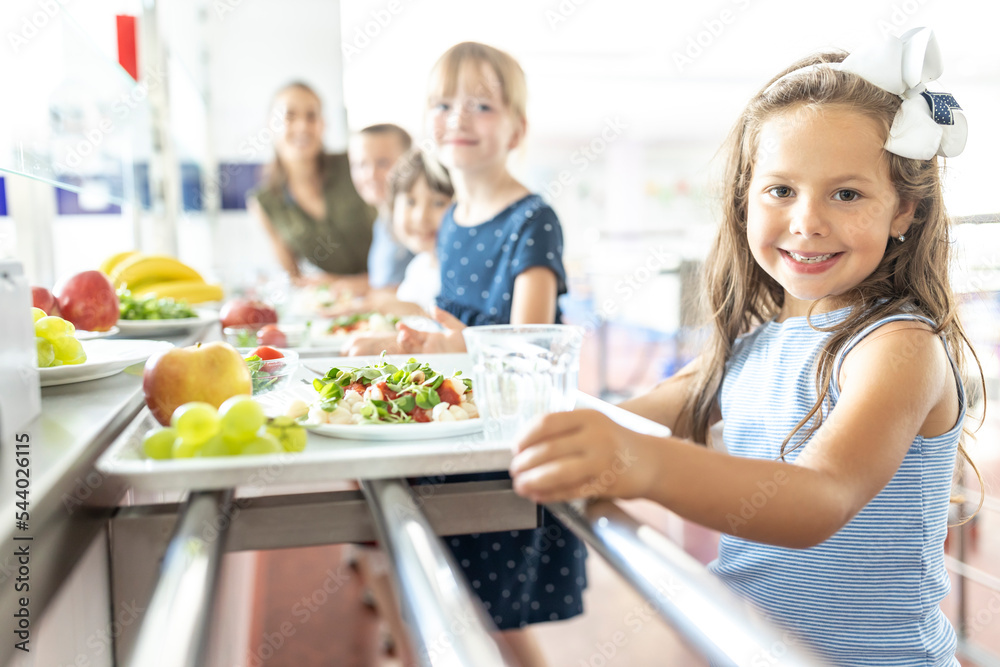 Smiling schoolgirl with fruits and food on tray at lunch break Smiling schoolgirl with fruits and food on tray at lunch break