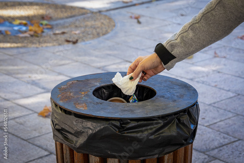 gros plan sur la main d'une personne jetant un papier dans une poubelle