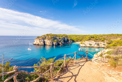 Spain, Balearic Islands, Menorca, Cliffs of Cala Macarelleta in summer with wooden fence in foreground photo