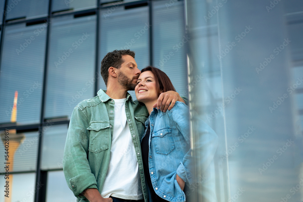 Man kissing woman on forehead standing in front of building Man kissing woman on forehead standing in front of building