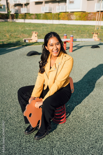 Happy woman sitting on spring horse at playground photo