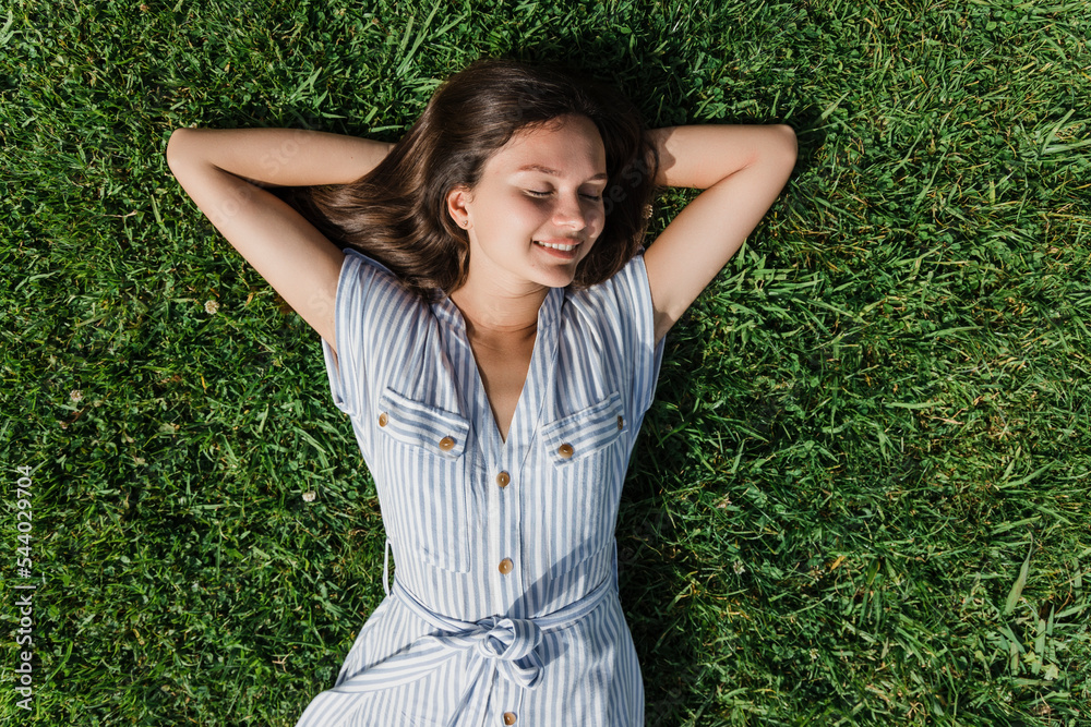Happy young woman with eyes closed relaxing on grass Happy young woman with eyes closed relaxing on grass