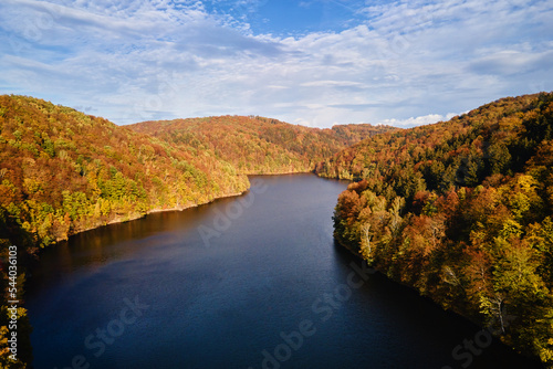 Aerial top view of amazing autumn landscape with mountains covered with forest and river. Beautiful nature landscape at fall season