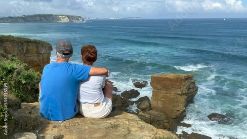 Couple sitting on the cliff by the sea
