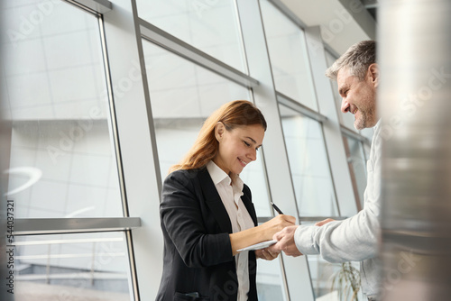 Woman boss signs adocument that employee is holding in hands