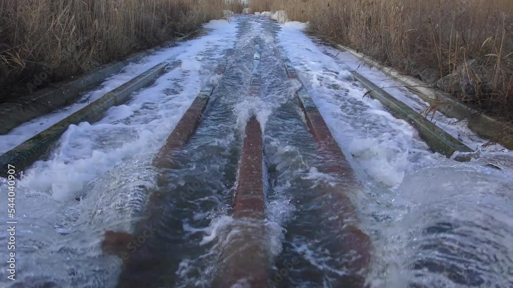 A powerful stream of dirty water escaping from the pipe rushes through