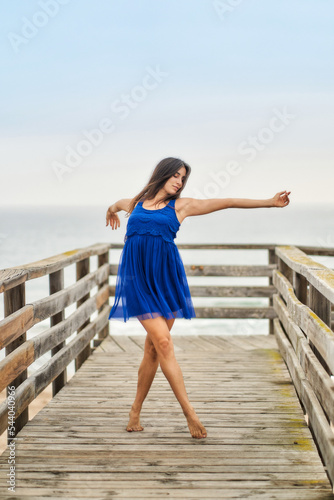 a dancer in a blue dress on the beach catwalk performing contemporary modern dance with strength and feeling