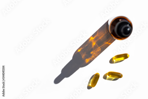 Fish oil capsules and bottle with drop shadow on white background. Top view, place for text.
