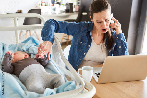 Gestresste Mutter betreut ihr Baby und telefoniert