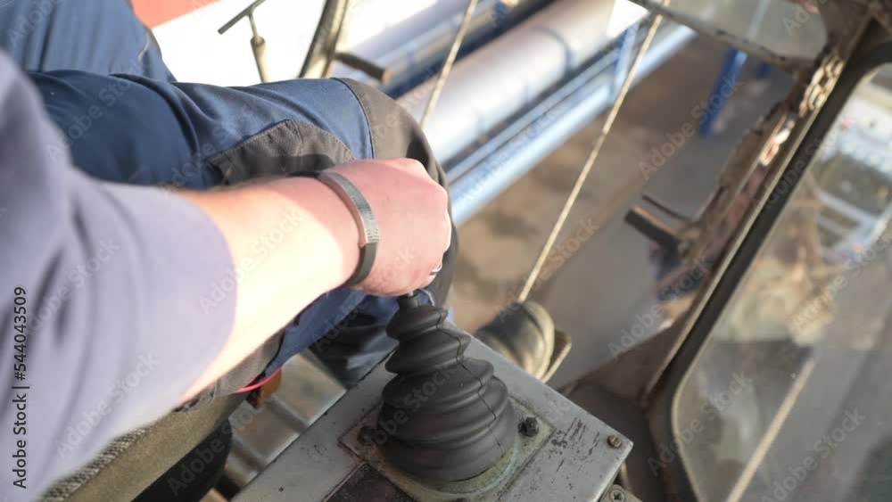 Crane operator controls crane with joystick, unloading gravel