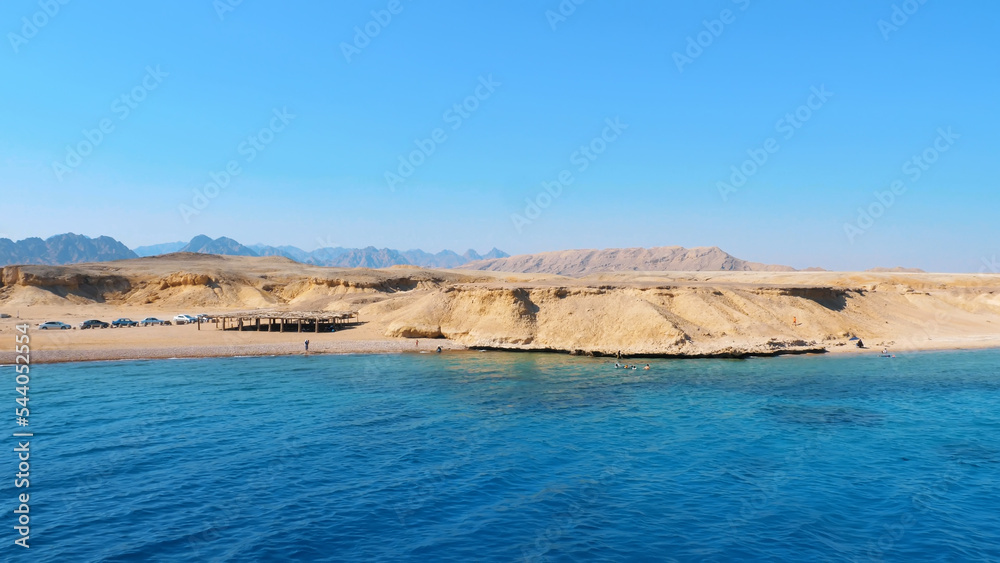 summer, sea, through a metal fence on the deck you can see a beautiful seascape. deserted shore, tents and machines of Bedouins. High quality photo