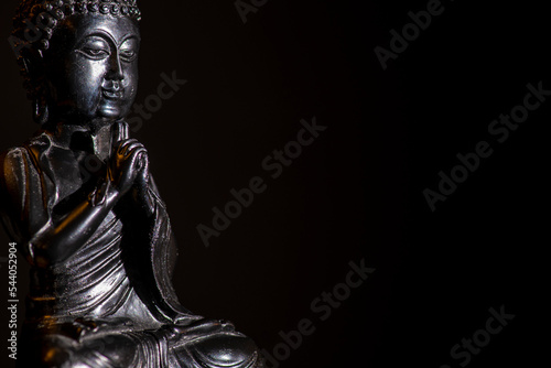 a low key shot of a black buddha statue with black background