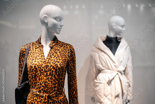 Two female mannequins in a shop window in a stylish leopard print shirt and jacket. Season trends 2023.