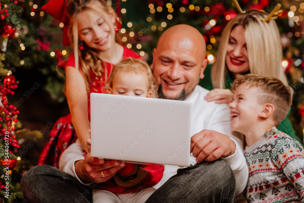 Big family of five people are doing online shopping by laptop in Christmas room Big family of five people are doing online shopping by laptop in Christmas room