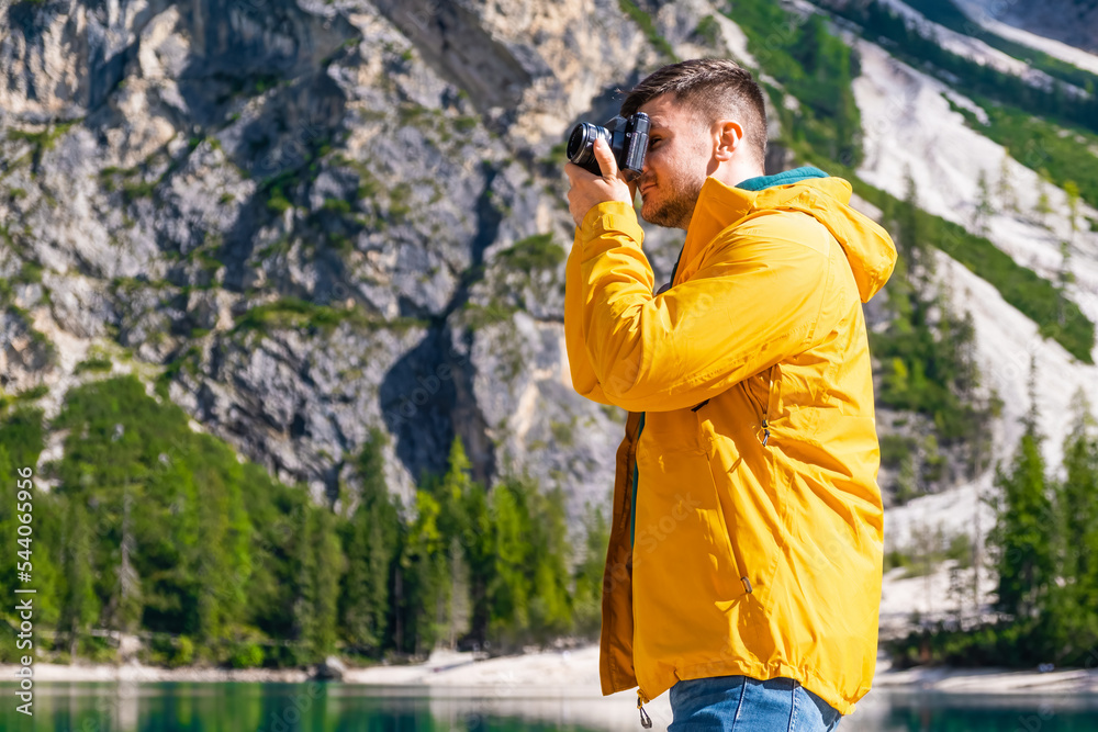 Handsome man taking photos of mountains and Lake Braies, Italy.