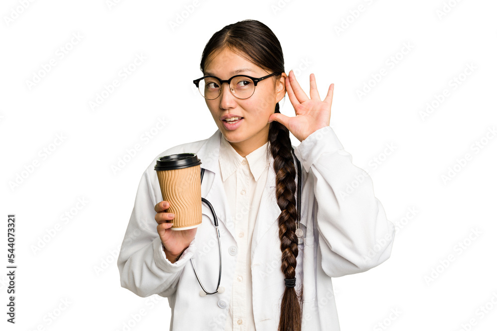 Young doctor asian woman holding a takeaway coffee isolated trying to listening a gossip. Young doctor asian woman holding a takeaway coffee isolated trying to listening a gossip.