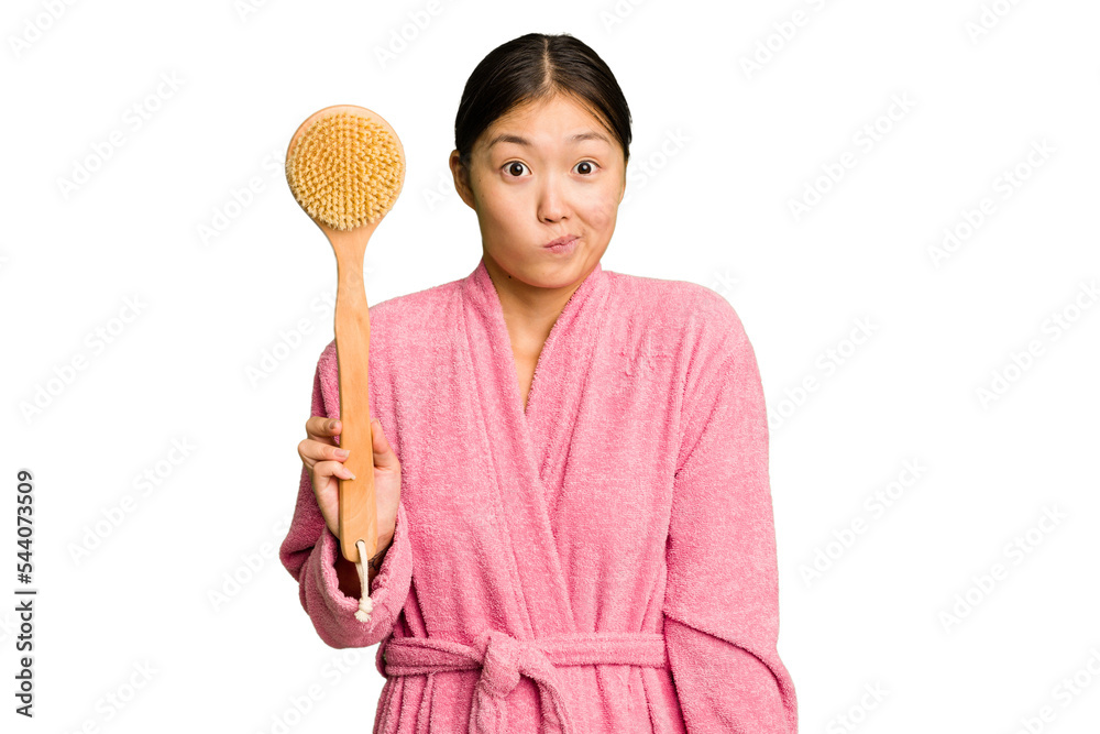 Young asian woman holding a shower brush isolated shrugs shoulders and open eyes confused. Young asian woman holding a shower brush isolated shrugs shoulders and open eyes confused.