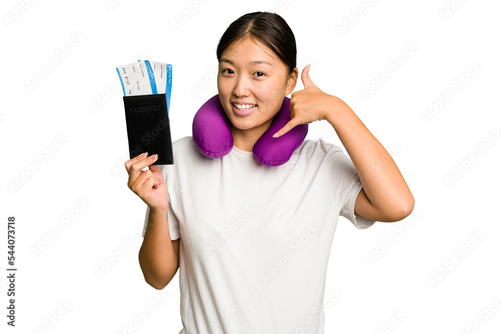Young asian woman with inflatable travel pillow on her neck holding passport isolated showing a mobile phone call gesture with fingers. Young asian woman with inflatable travel pillow on her neck holding passport isolated showing a mobile phone call gesture with fingers.