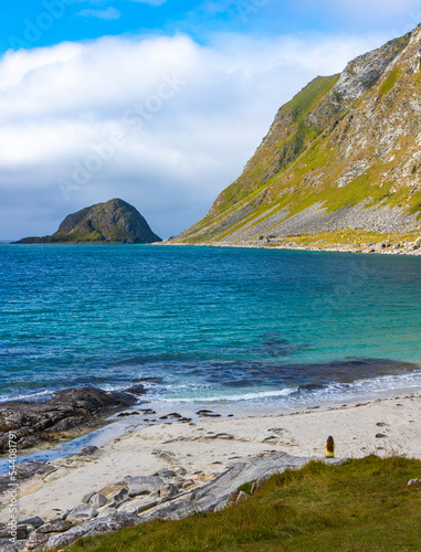 aerial photography of long-haired girl walking on famous haukland beach in norway on lofoten islands; paradise beach in norwegian fjord with mighty mountains