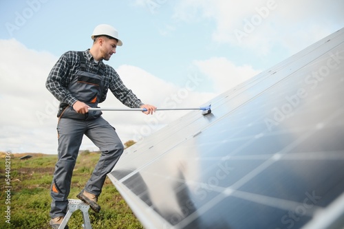 A worker cleaning dust and dirt form solar panels.