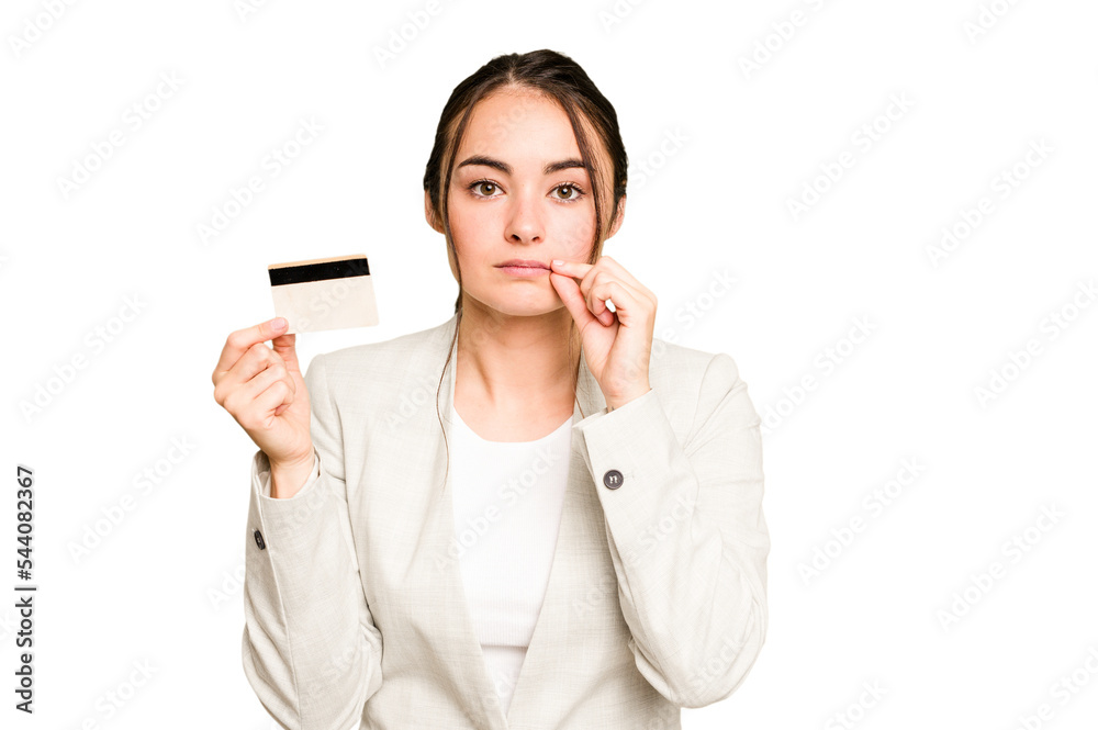 Young caucasian woman holding a credit card isolated on green chroma background with fingers on lips keeping a secret. Young caucasian woman holding a credit card isolated on green chroma background with fingers on lips keeping a secret.