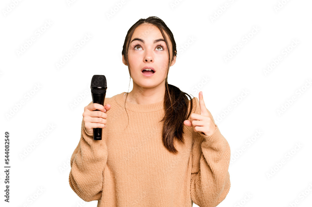 Young caucasian singer woman isolated on green chroma background pointing upside with opened mouth. Young caucasian singer woman isolated on green chroma background pointing upside with opened mouth.