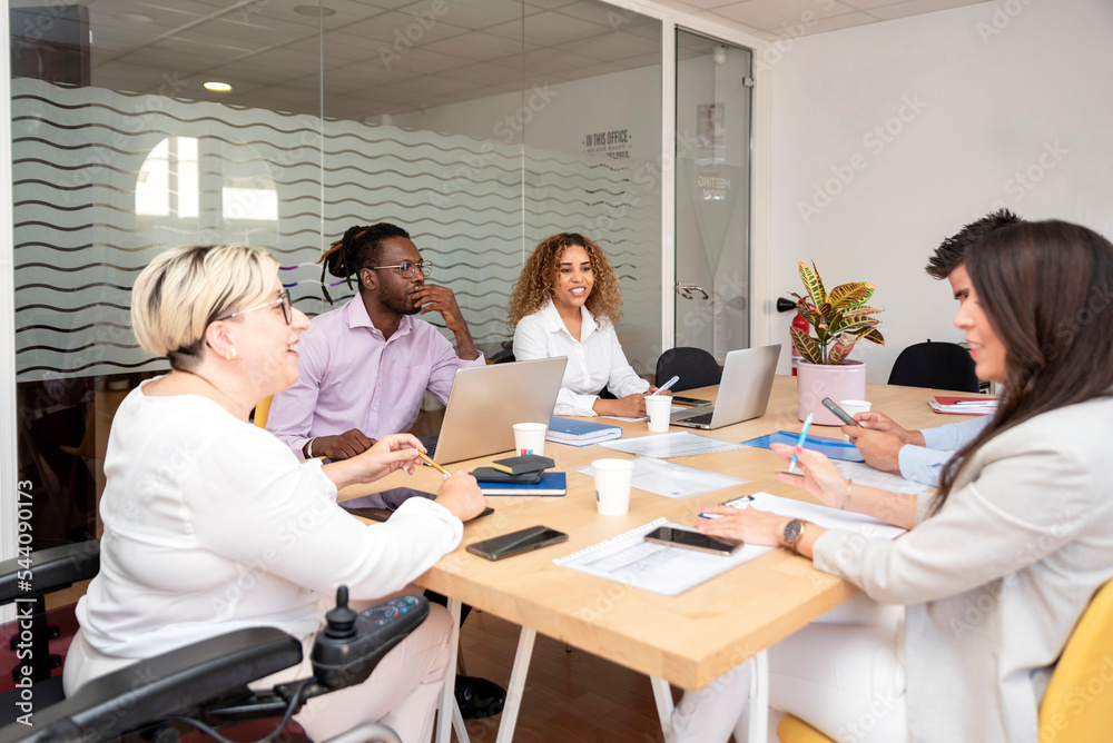 businesswoman in the wheelchair leads a multiracial group at the meeting businesswoman in the wheelchair leads a multiracial group at the meeting