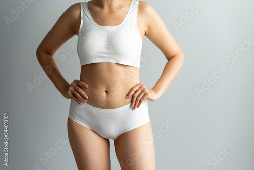 Fototapeta Naklejka Na Ścianę i Meble -  Cropped image of sexy attractive young woman in white underwear showing fit body standing posing hold hand on hips legs isolated on white wall background studio portrait