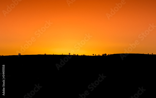 warm sunset over a mountain ridge with trees in silhouette in the hills of North Macedonia