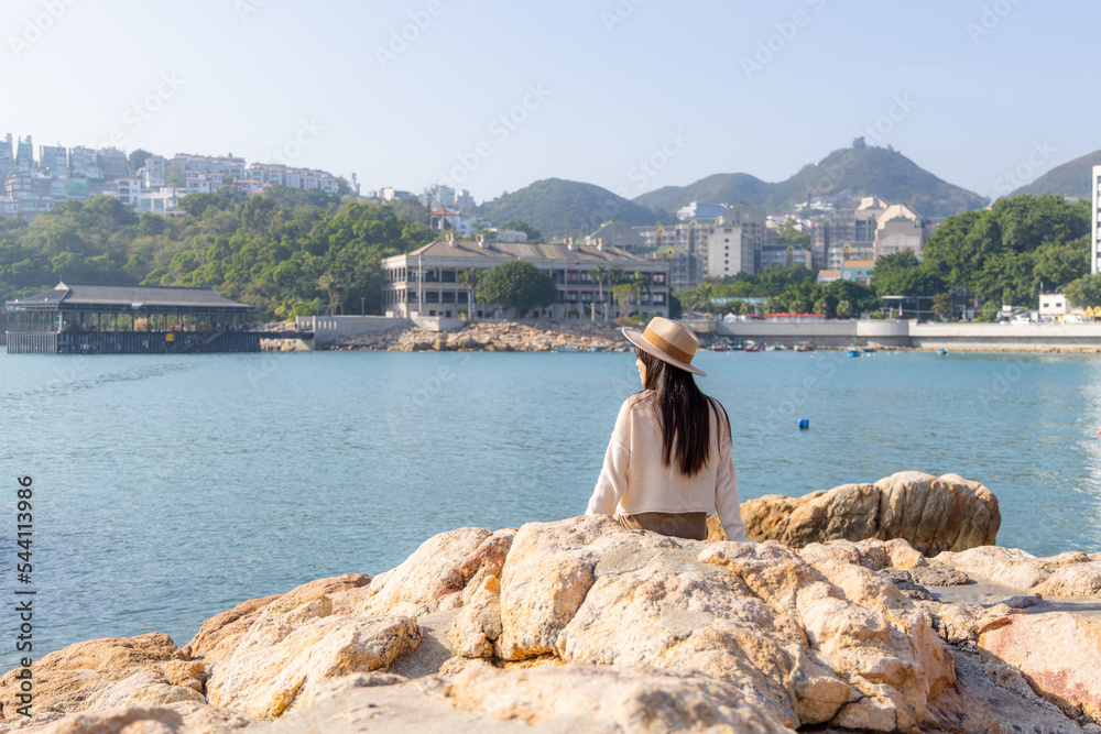 Tourist woman sit on the rock and enjoy the sea view in Stanley of Hong Kong city Tourist woman sit on the rock and enjoy the sea view in Stanley of Hong Kong city
