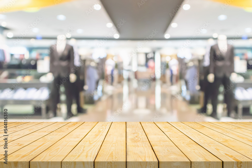 Fototapeta premium Empty wood table top with blur clothing boutique display interior shopping mall background