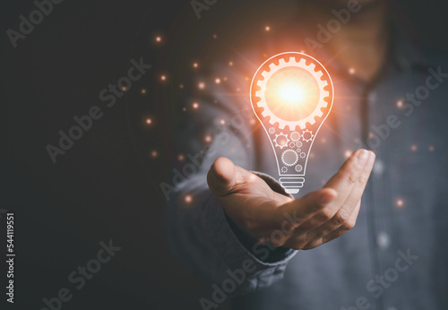 Idea and inspiration concept. Business man shows light bulb with gear and brain inside for idea and new inspiration with high technology.